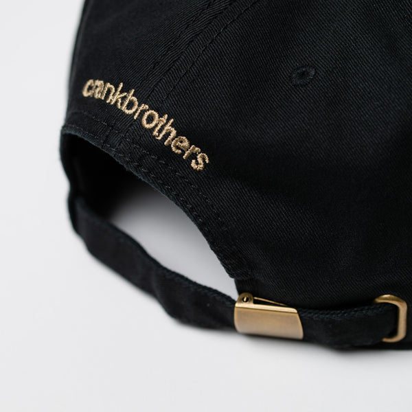 Black cap with ' crankbrothers' logo on a light gray background